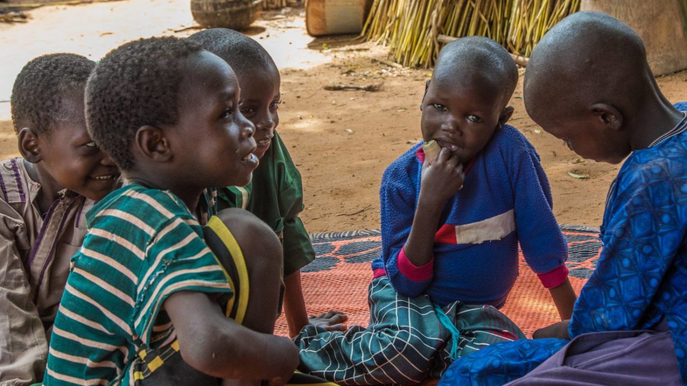 Muzi sitting outside with four other young boys.