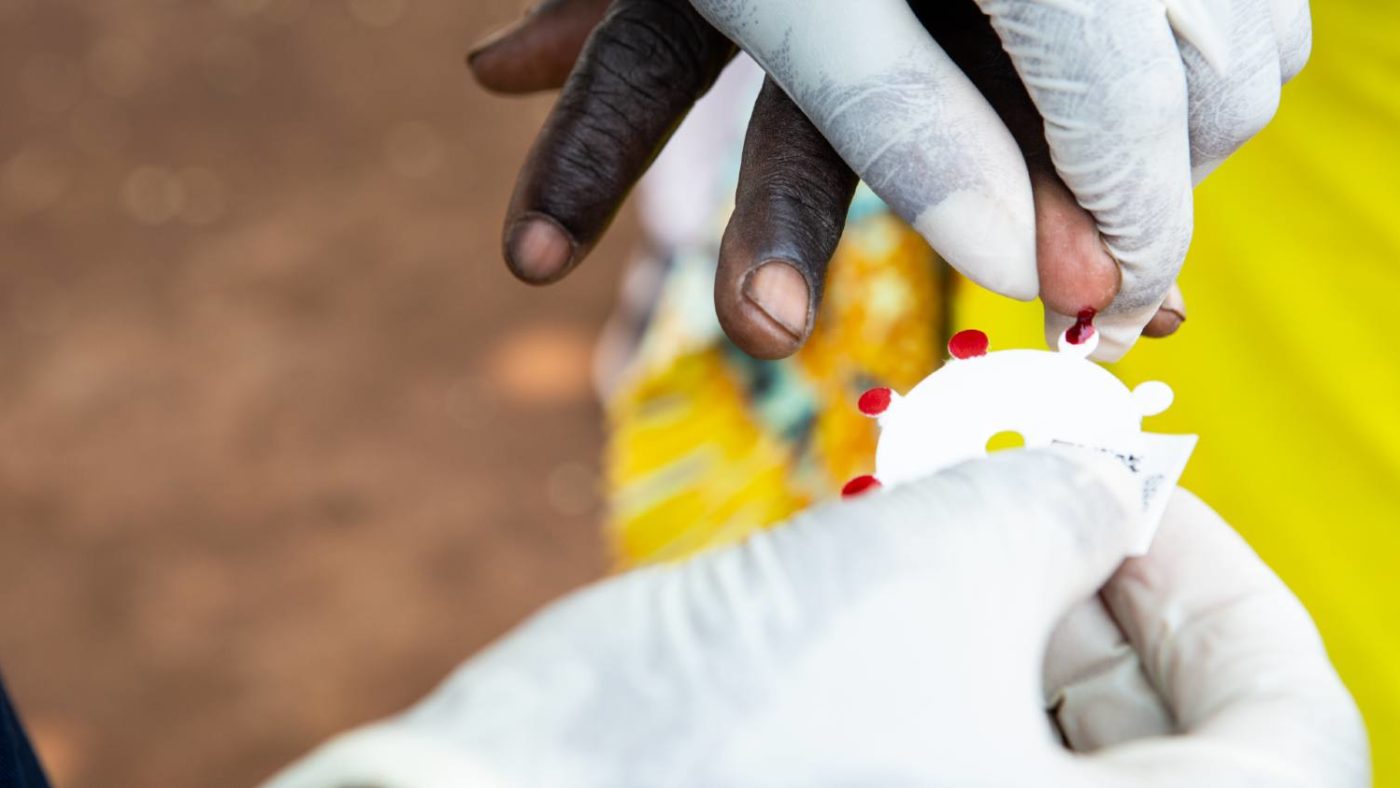Close up image of dry blood spot sample being taken and placed on circular filter paper.