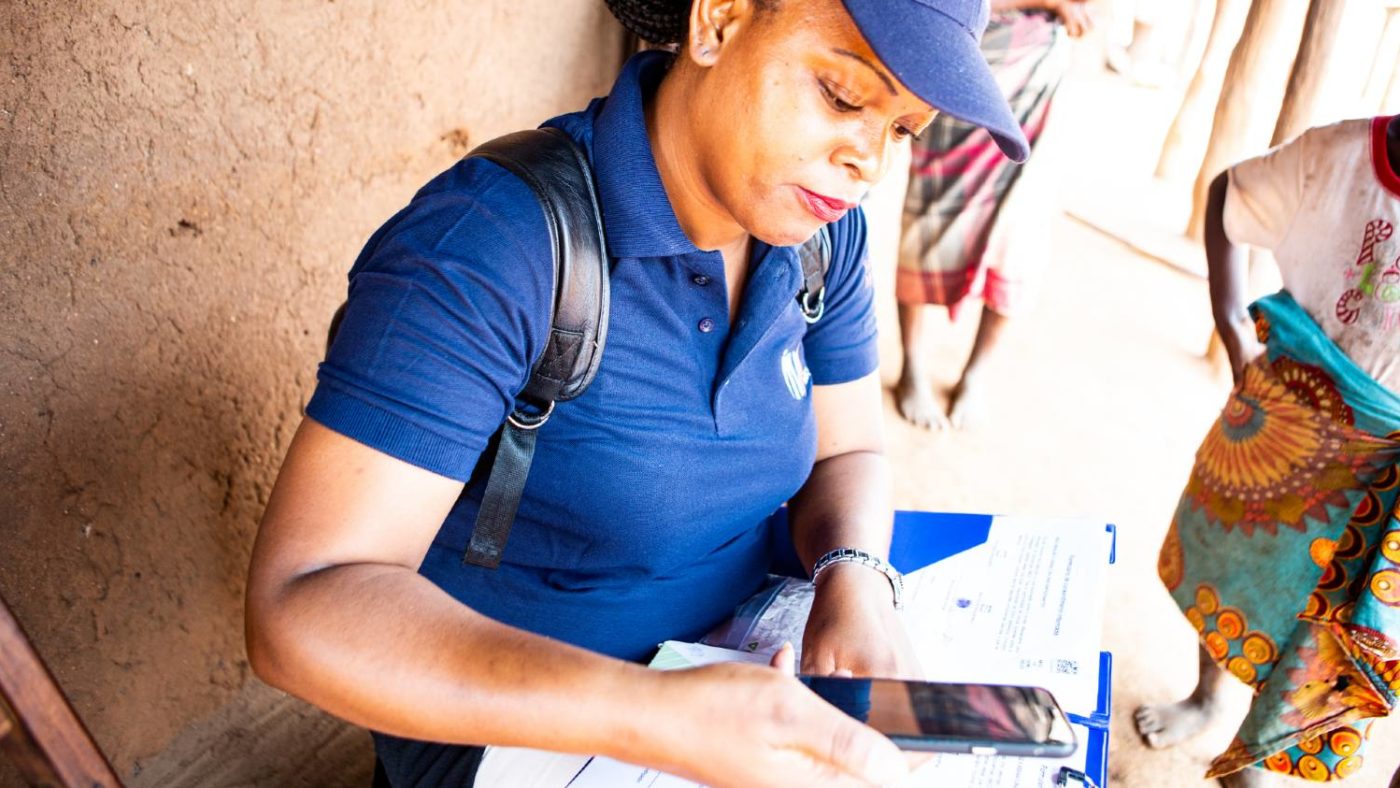 A woman enter data into a mobile phone.