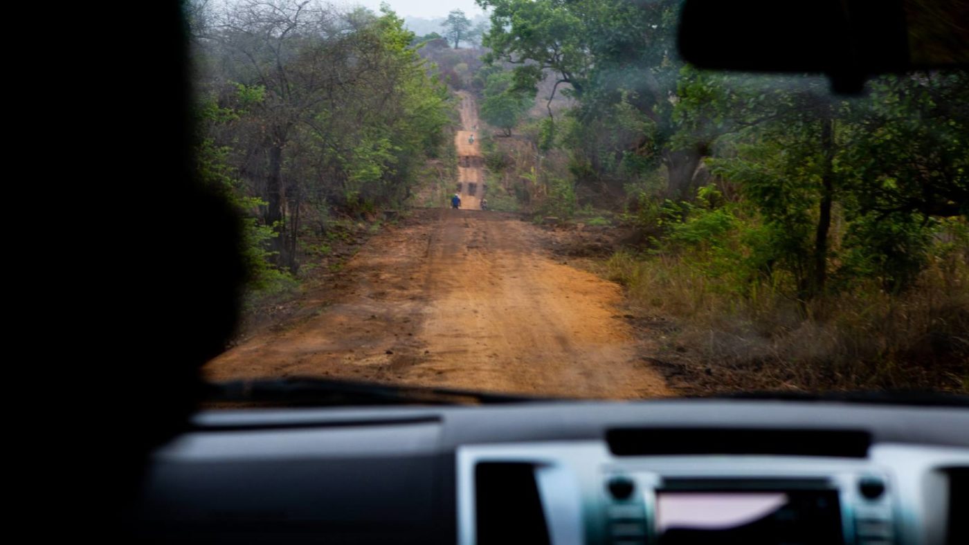 A bumpy dirt road in Zambezia Province as seen through the front window of a car