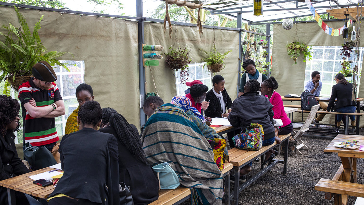 A group of people sit in a cafe, working on paper together.