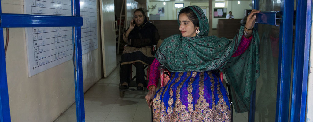 A woman using a wheelchair leaving a building.