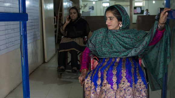 A woman using a wheelchair leaving a building.