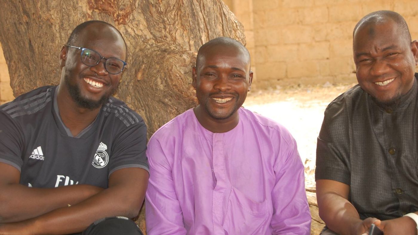 Three men sit next to each other for a photo.