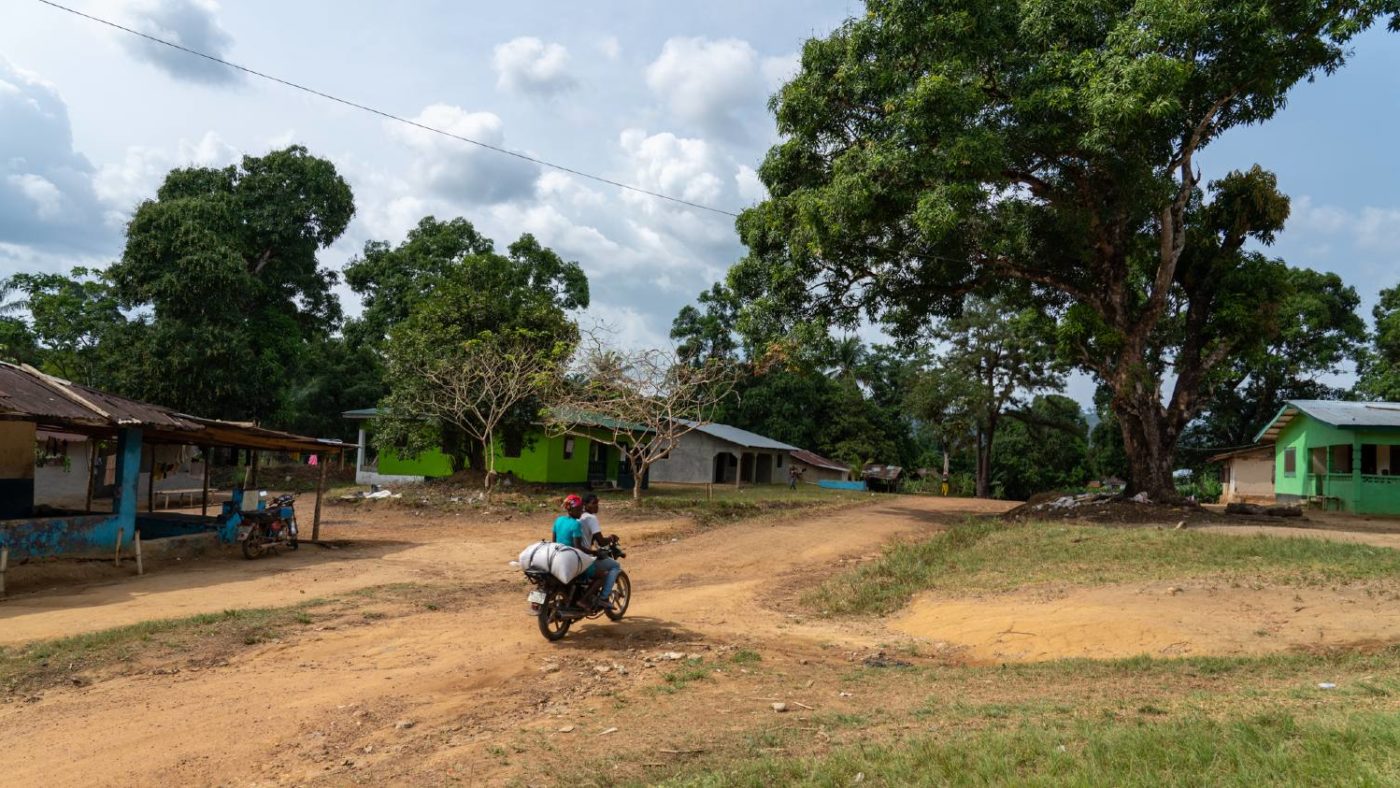 Two people ride off into the distance on a motorbike.