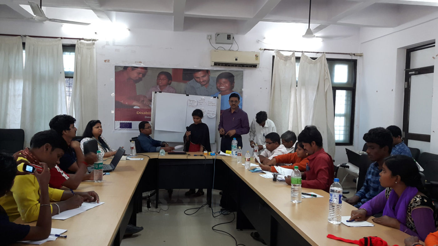 A group of people sitting around a U-shaped boardroom table.