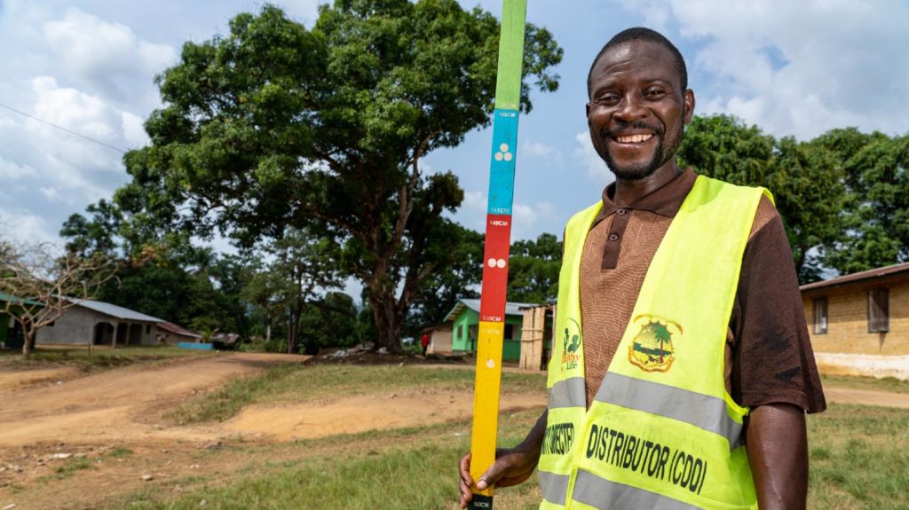 A man stands for a portrait while holding a colourful dose pole.