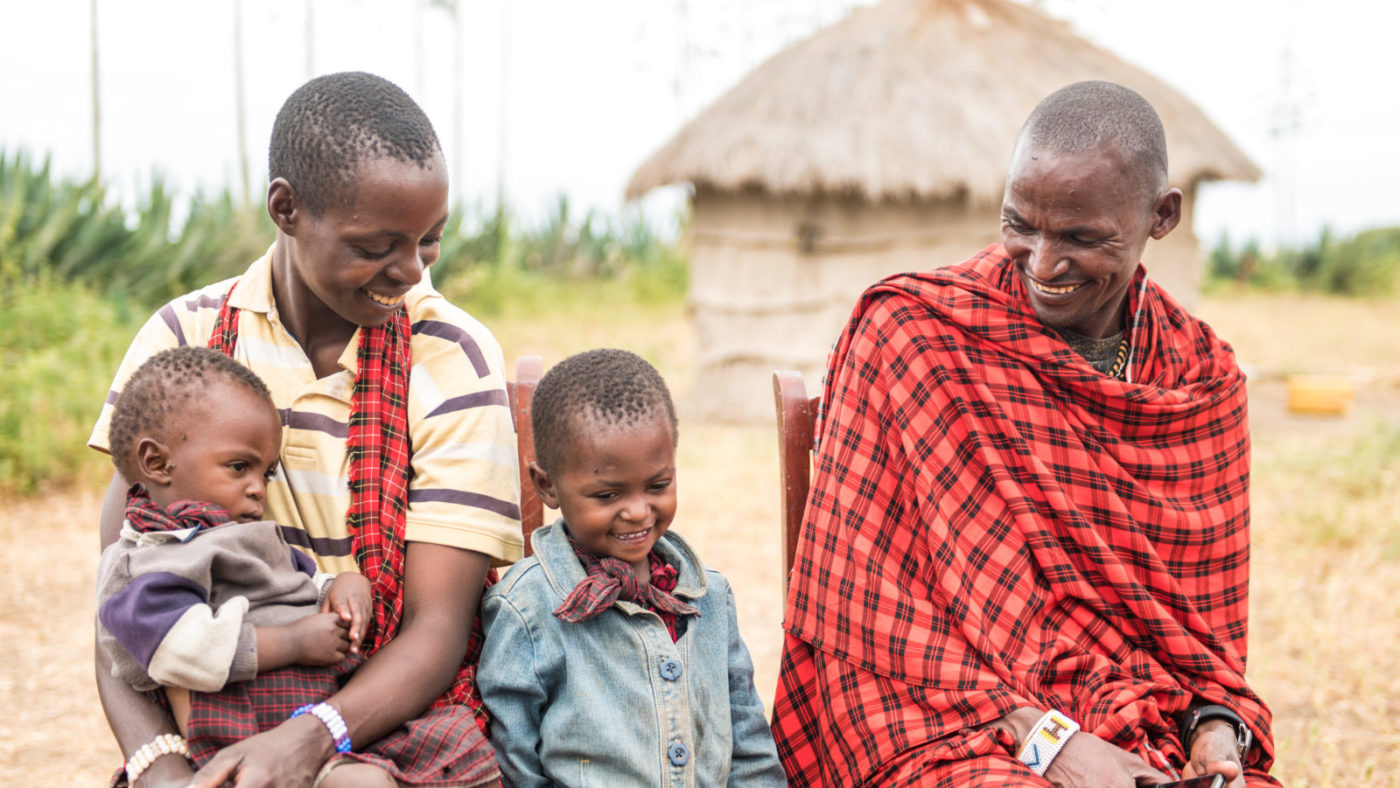 A smiling young boy sits with his family.