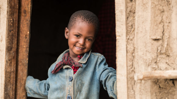 Four-year-old Paolo stands smiling in a doorway.