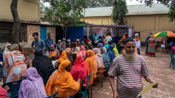 Many people sit outside waiting for an eye examination.