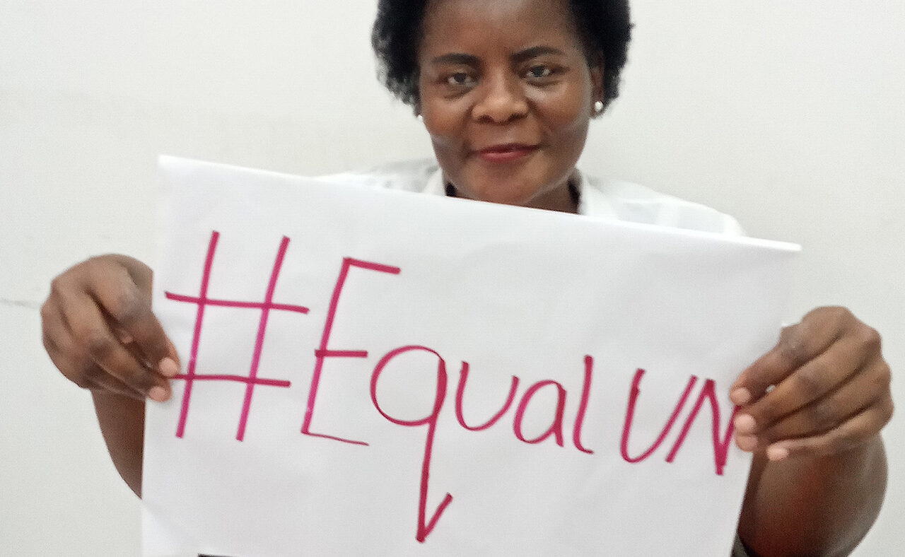 Eufémia Amela smiles and holds a sign saying #EqualUN.