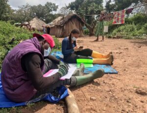 Two people sit outside inputting data.