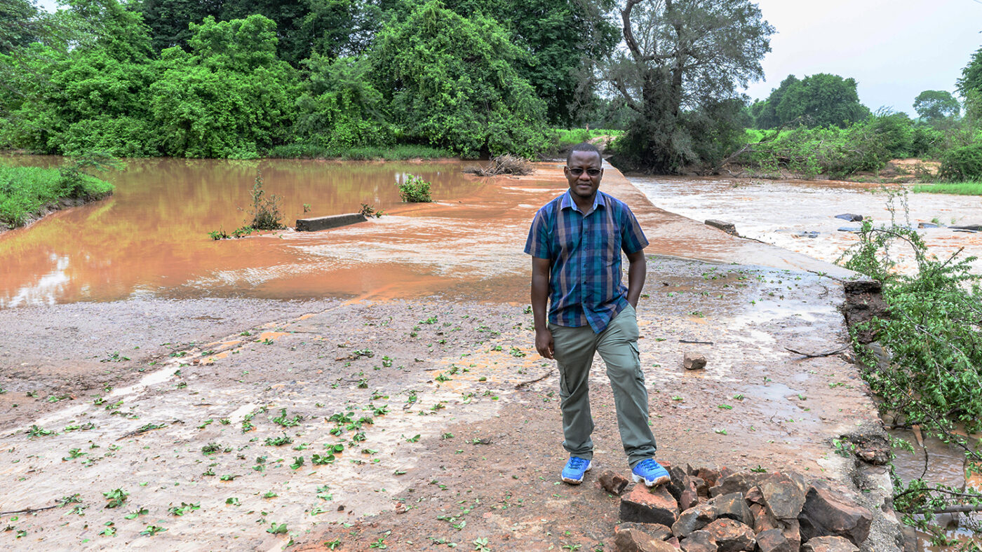 Senior programmes lead in Zimbabwe, Peter Bare, stands in front of a flooded road.