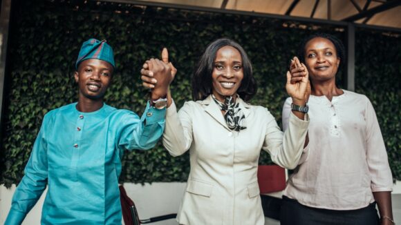Three people holding hands and smiling.