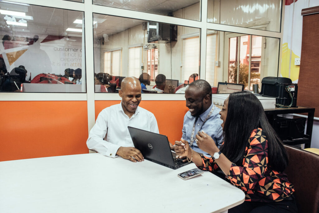 Three people sit round a desk.