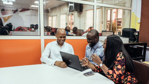 Three people sit round a desk.