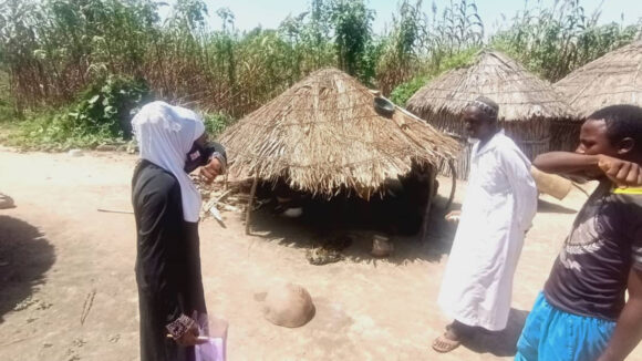 A woman shows two men how correctly cover their mouths when the cough.