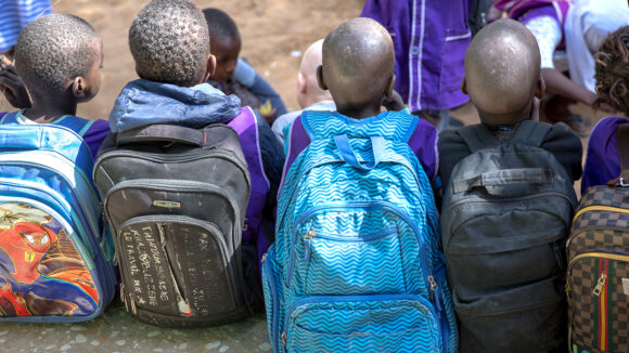 Children sit closely together outside.