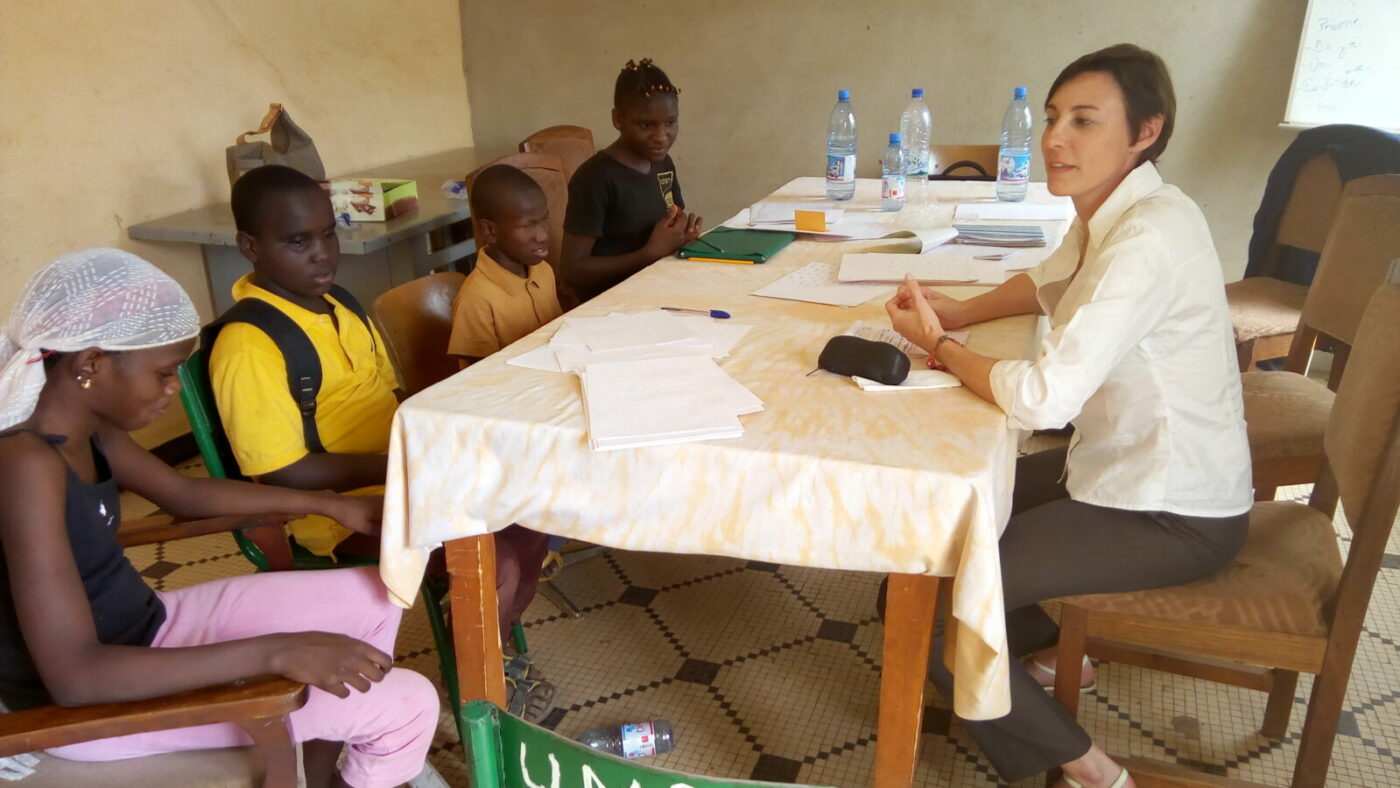 Two children sit at a table with a woman.