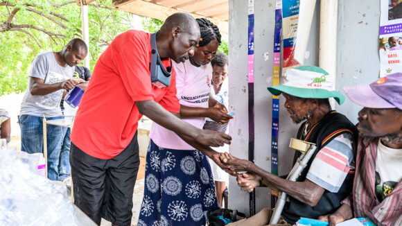 A community volunteer gives a man some medication.