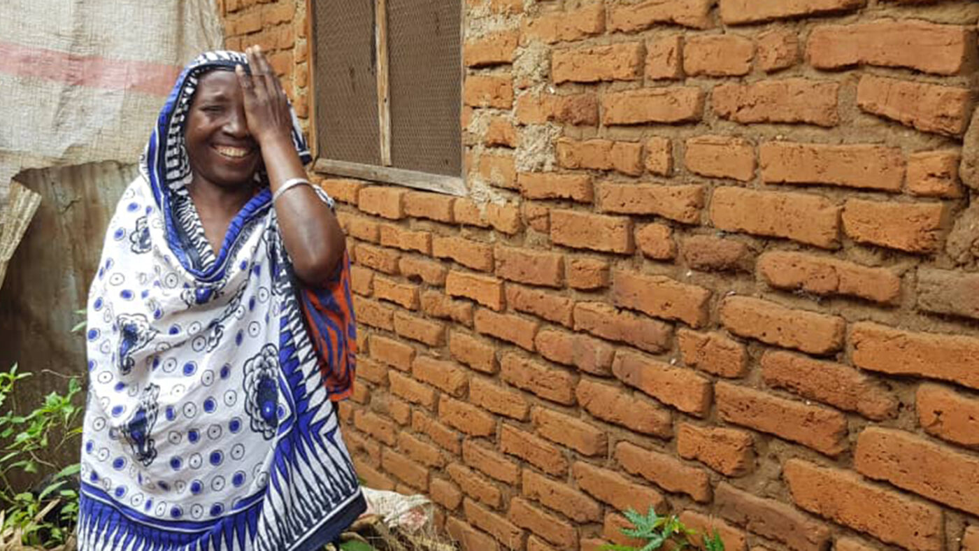 Amina smiles as she covers one of her eyes with her hand.