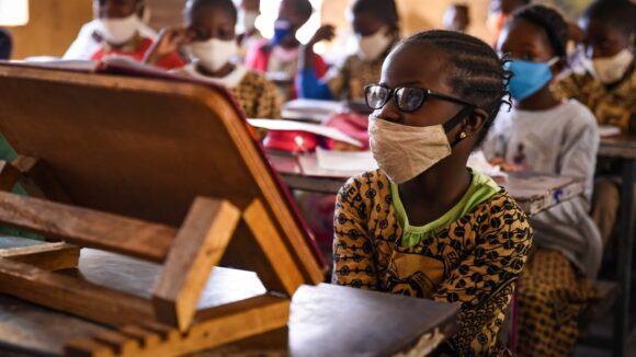 Mariam sits in a classroom wearing a face covering.
