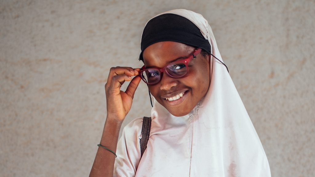 Close up of 12 year old Rukayya proudly wearing and holding her new glasses