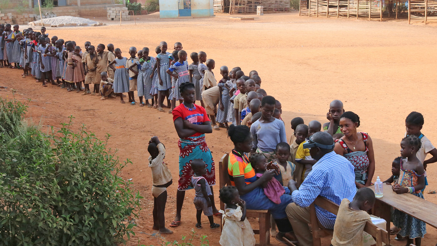 A long line of children queue to see an eye health worker.
