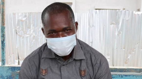 Dr Dje Norbert looks at the camera while wearing a mask.