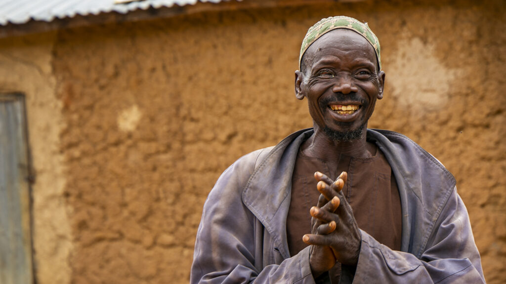 Adou smiles outside his home.