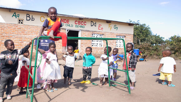A group of young children playing on a climbing frame outside a school