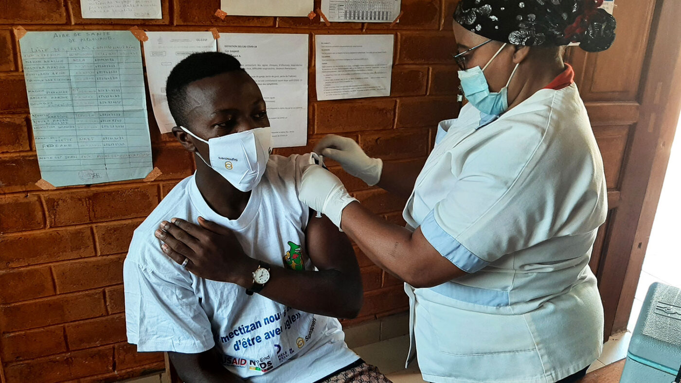 A man is given the COVID-19 vaccine by a health care worker.