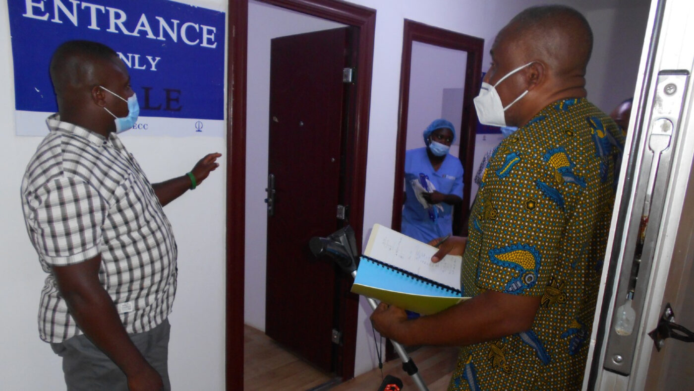 Two men in masks are inside a treatment facility conducting an audit.