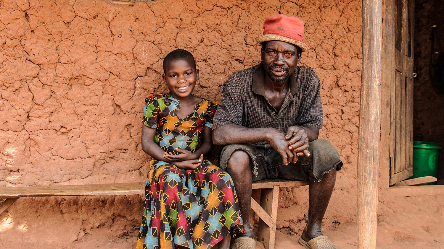 A young girl sits smiling next to her father.