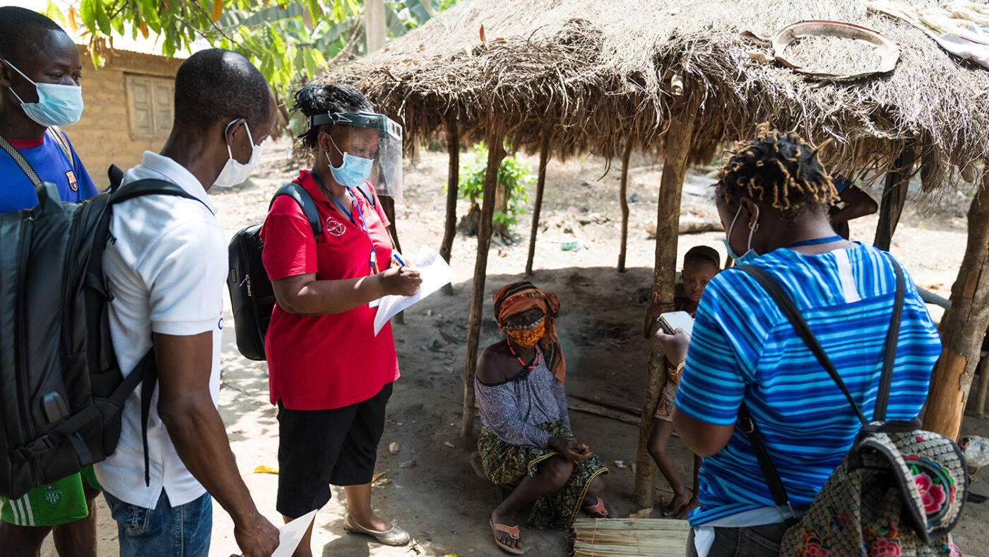 Three eye health workers wearing masks speak to local villagers.