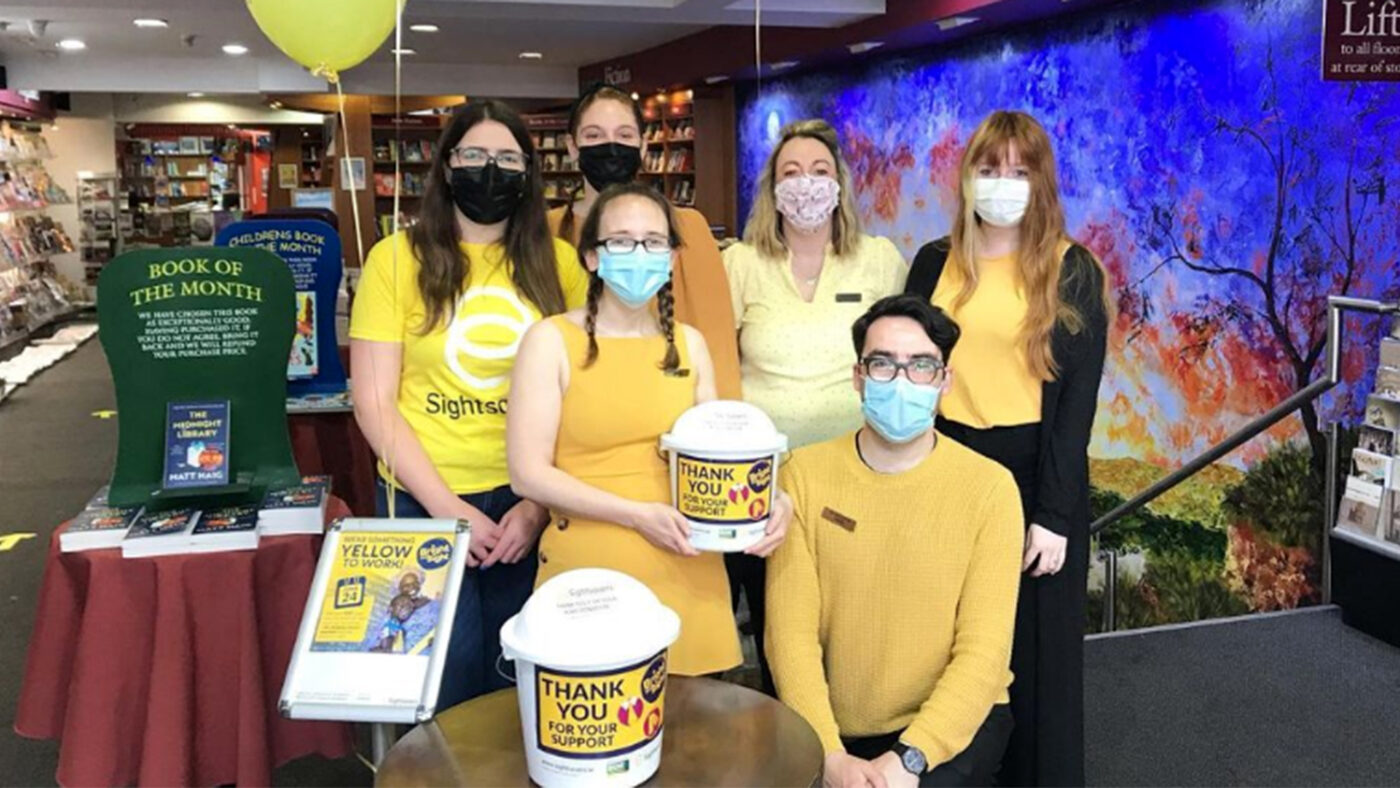 A group of people wearing yellow outfits and holding fundraising buckets.