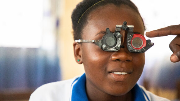 A girl smiles as she has her eyes checked during a vision screening in Libera.