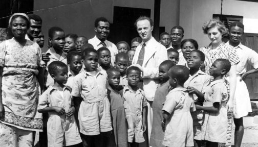 A historic black and white photo with Sightsavers founder Sir John Wilson and his wife Lady Jean surrounded by staff and children from Akropong school in Kenya.