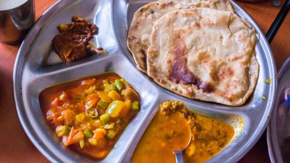 A metal plate full of Indian food.
