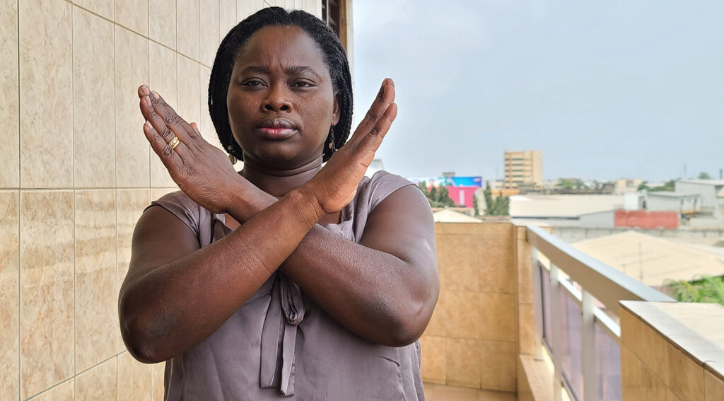 Pelagie stands while holding her arms crossed in front of her chest.