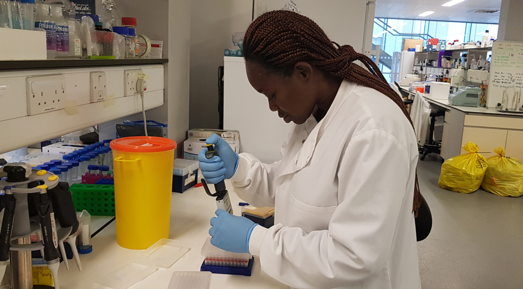 Pelagie wears a white lab coat and analyses samples in a laboratory.