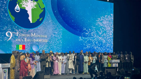 A large group of people stand on the main stage at the World Water Forum.