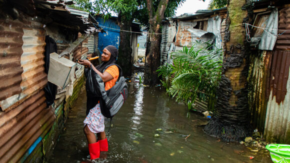 A woman collects mosquito samples from a flooded area in Liberia.