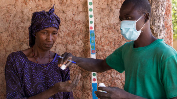A woman receives medication to treat river blindness from community volunteer.