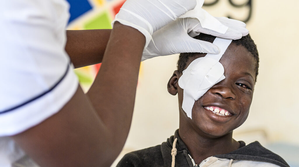 Agnes smiles brightly as a doctor removes a bandage from her right eye.