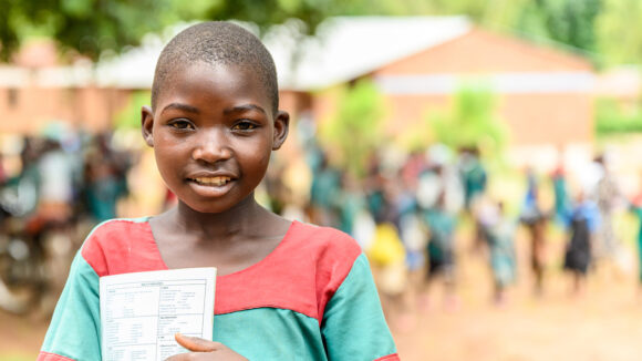 Mary stands holding a book after her cataracts operation.