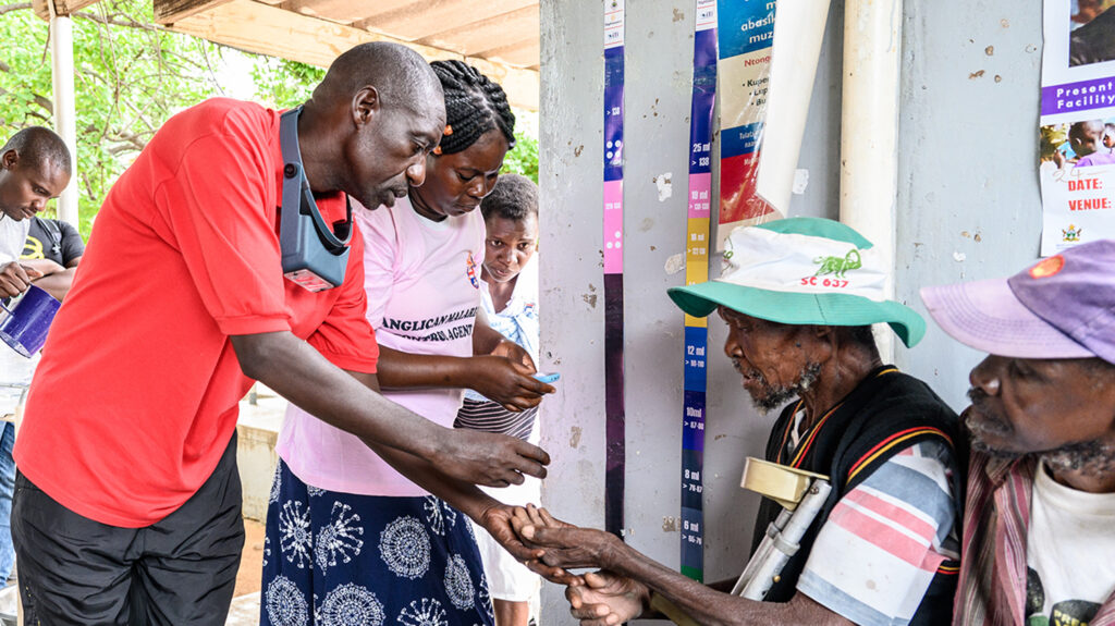 Ophthalmic nurse Jeremiah Gwafa and a colleague hand medication to an elderly male patient.