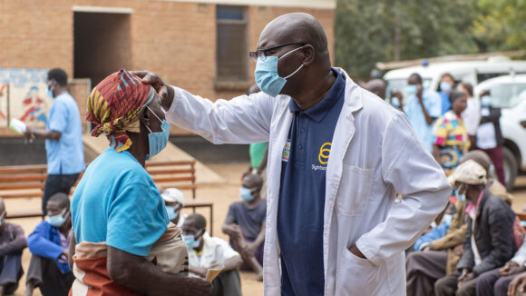 Ophthalmic clinical officer Rex performs an eye test on a woman at an outdoor community screening.
