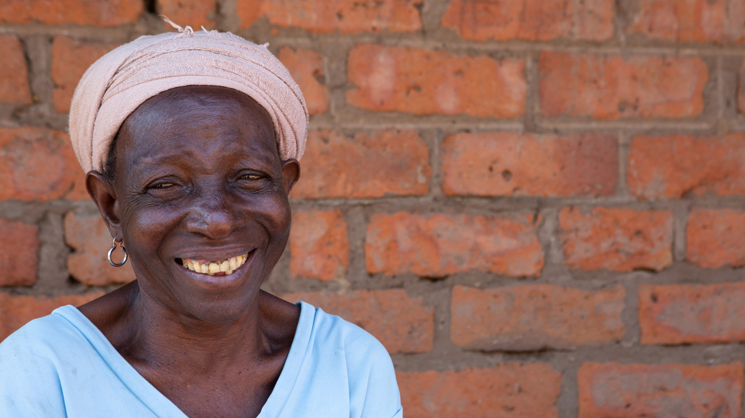 Achiwa smiles outside her home.