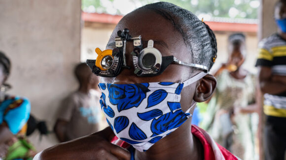 Nowah wears optometry glasses during an eye test at her school in Liberia.